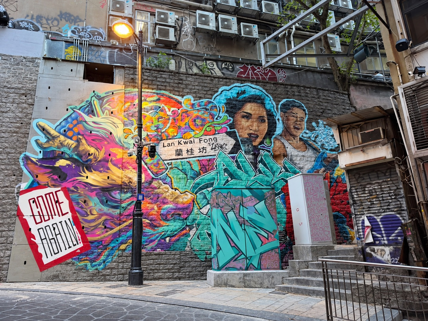 Colourful street art at the D’Aguilar Street entrance to Lan Kwai Fong, featuring a dragon, street sign and Canto-pop portraits.